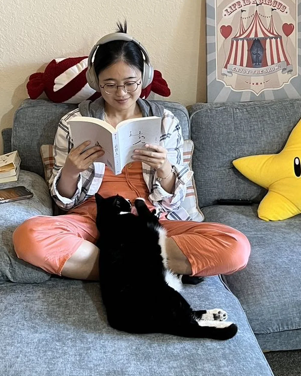 Yaxuan reading on a sofa with a cat